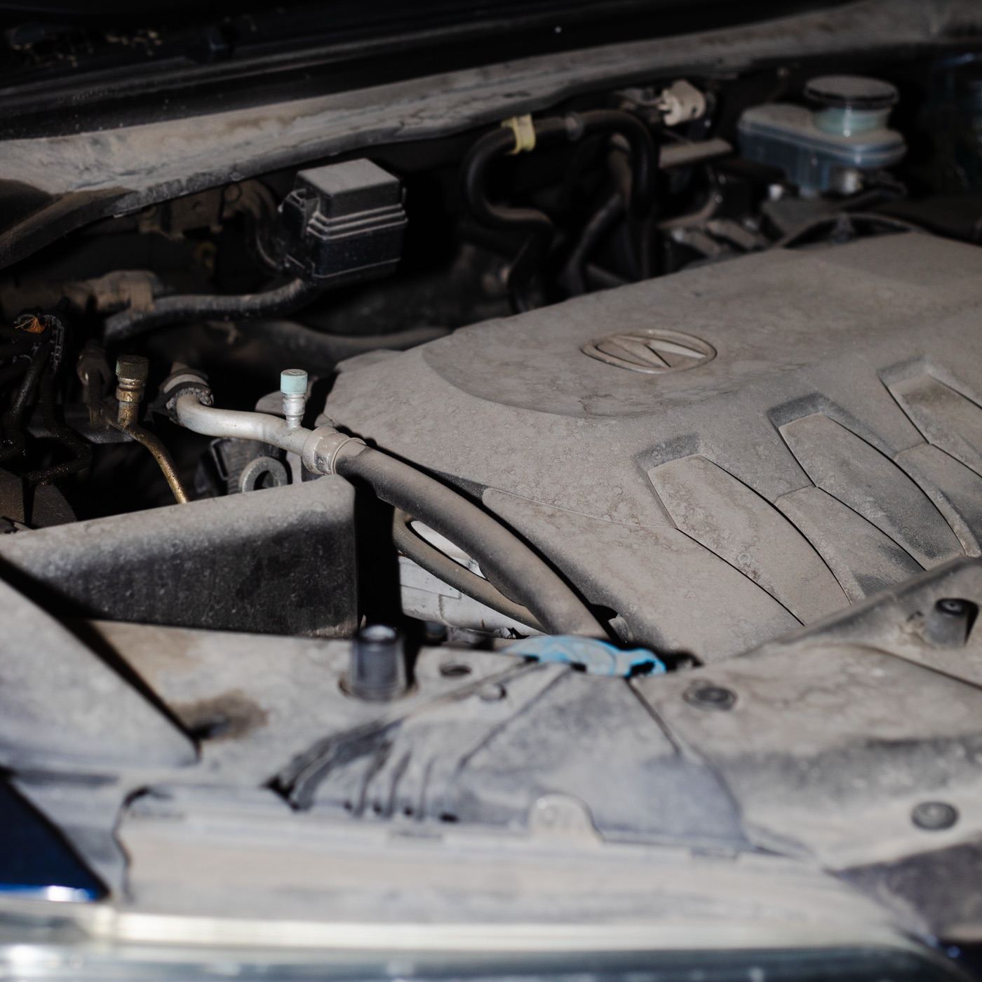Acura RDX engine bay covered in dust before detail
